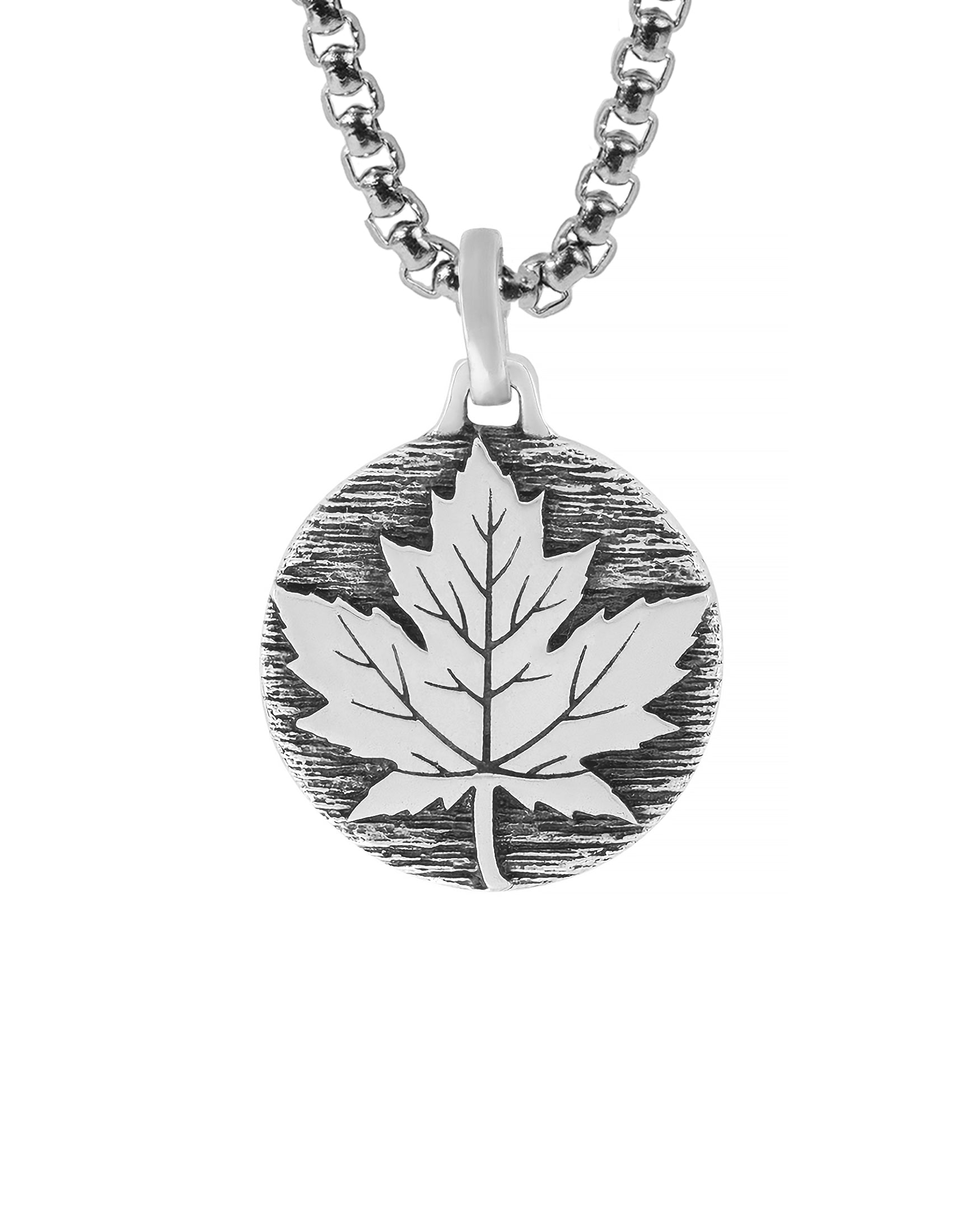 sterling silver round necklace pendant with maple leaf on a tree bark.