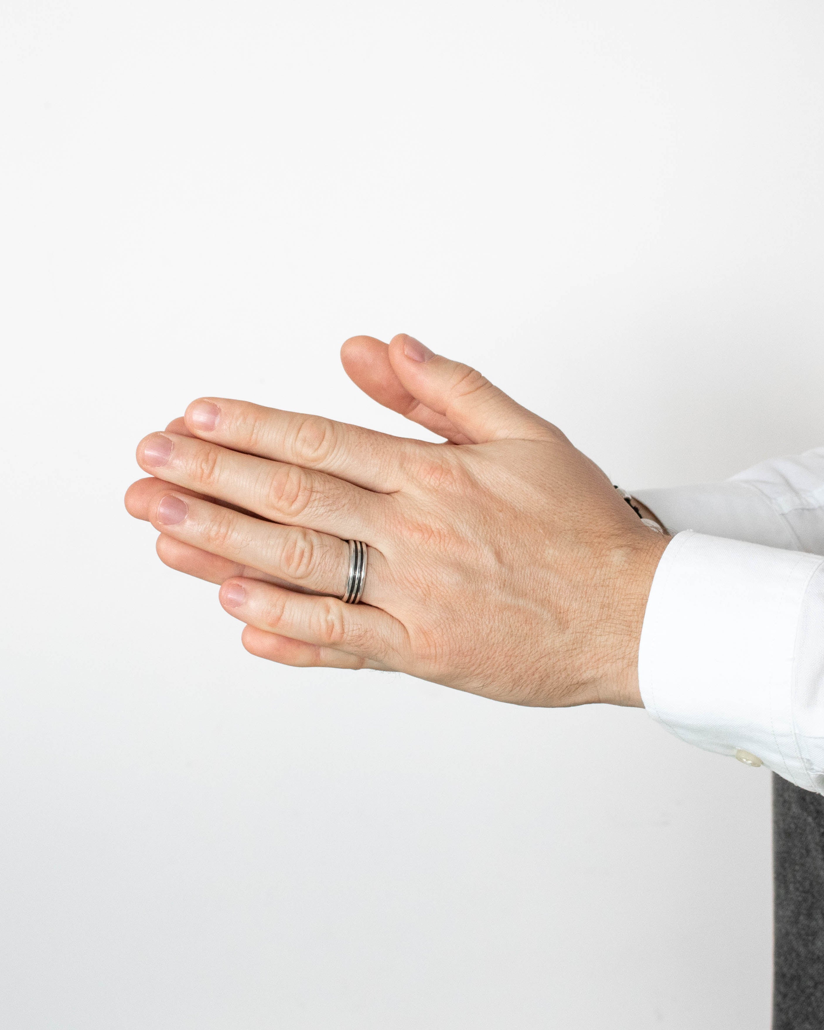 Close-up of a person's hands with a ring on a white background
