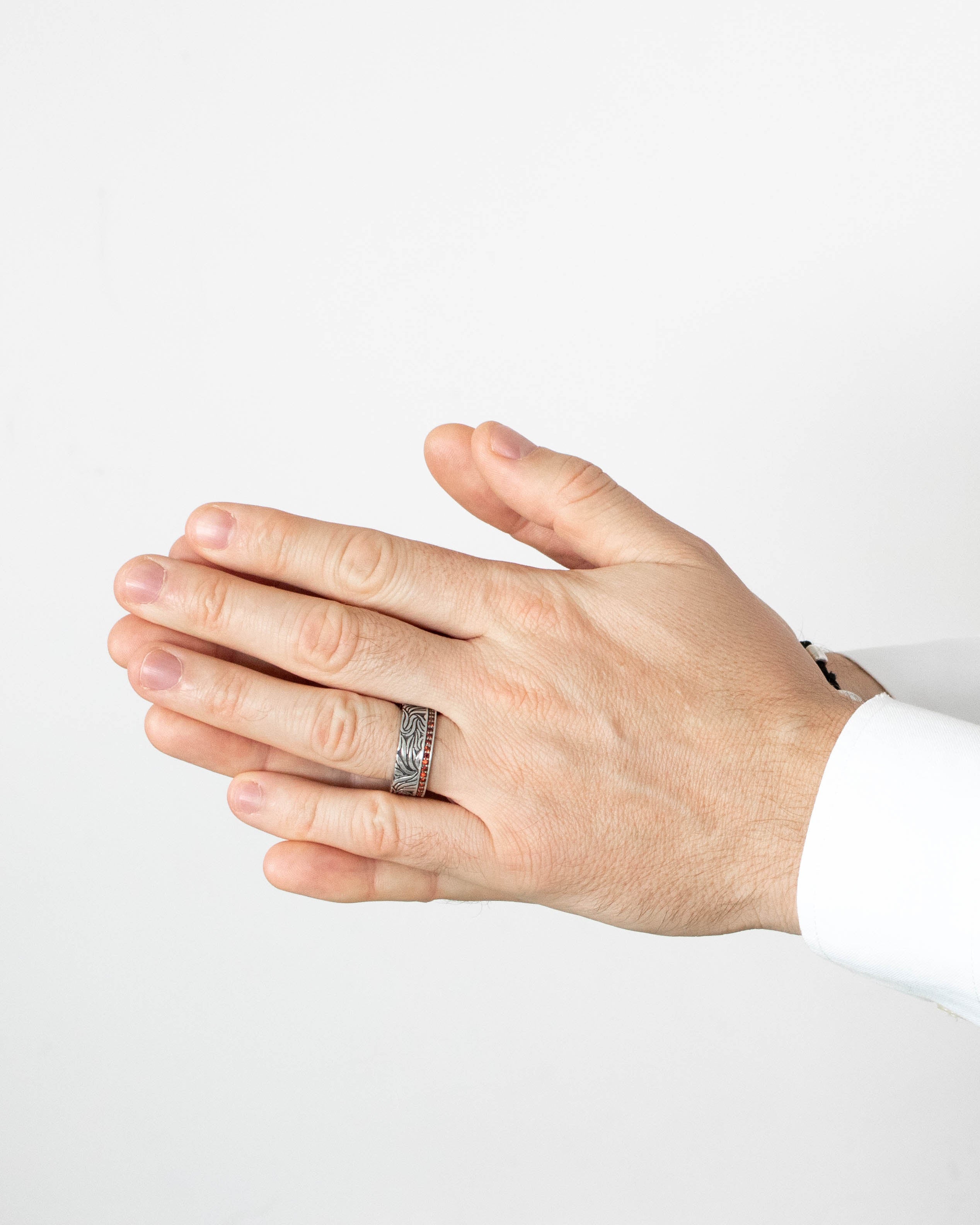 Hand wearing a silver ring on a plain background