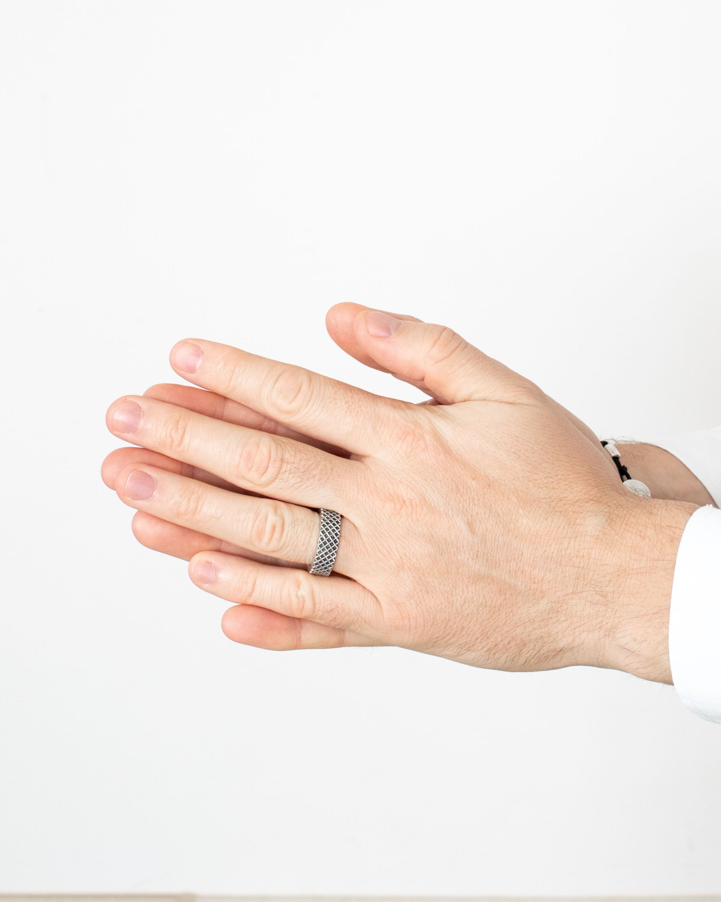 Hand wearing a silver ring on a plain background