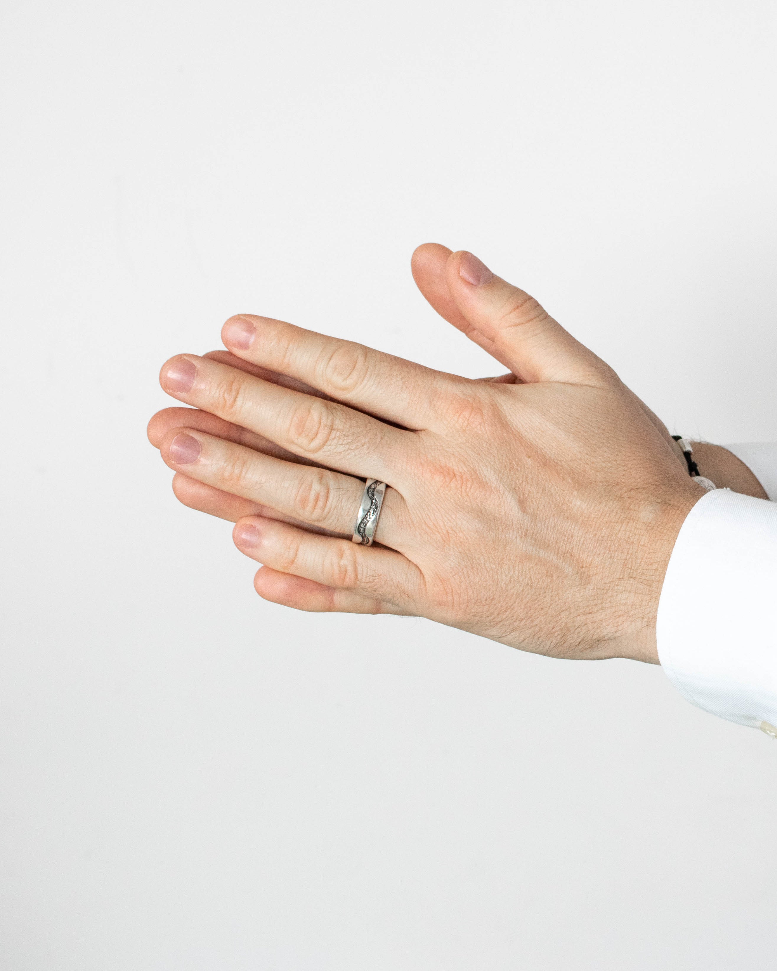Hand wearing a ring on a plain background