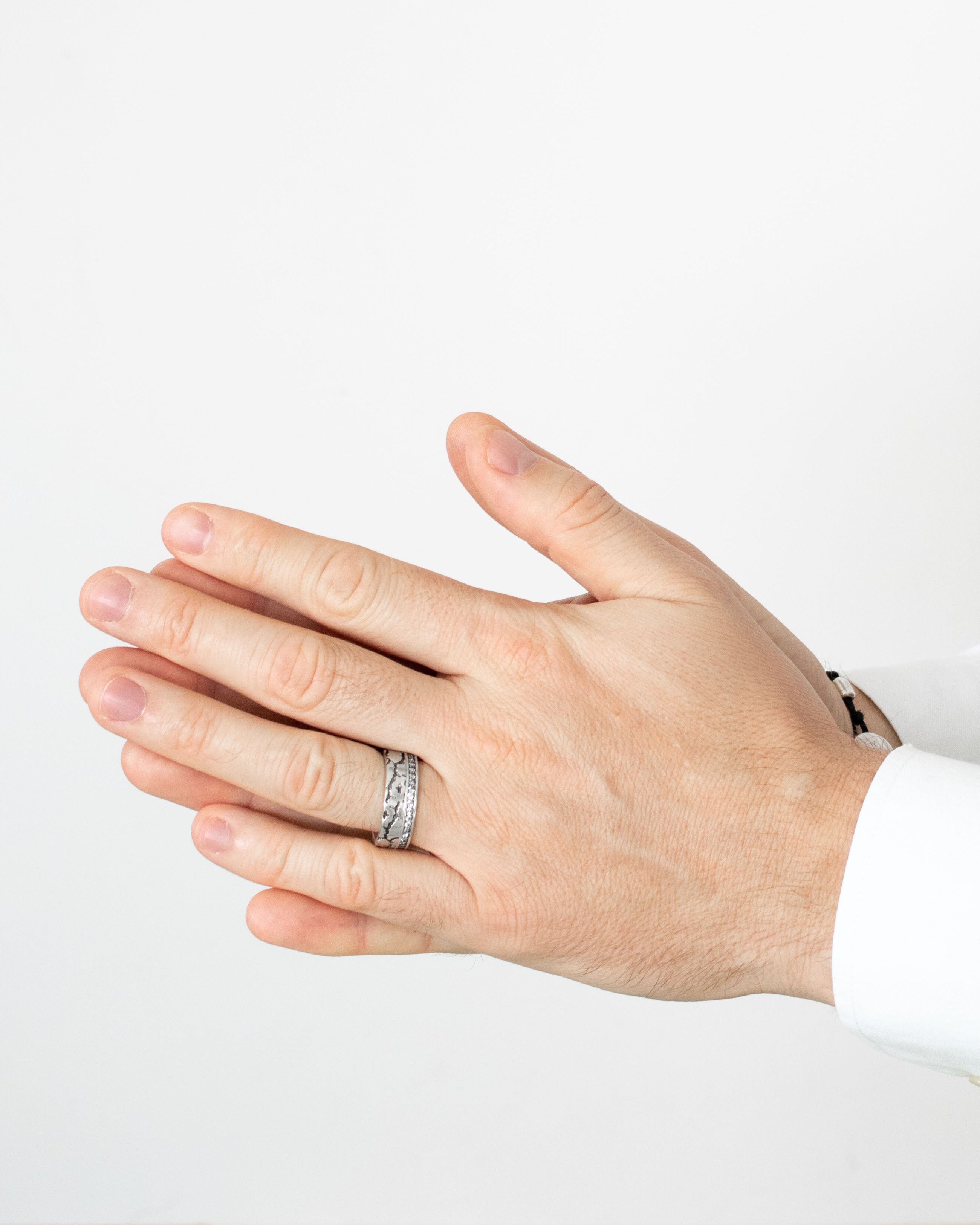 Hand wearing a silver ring on a white background