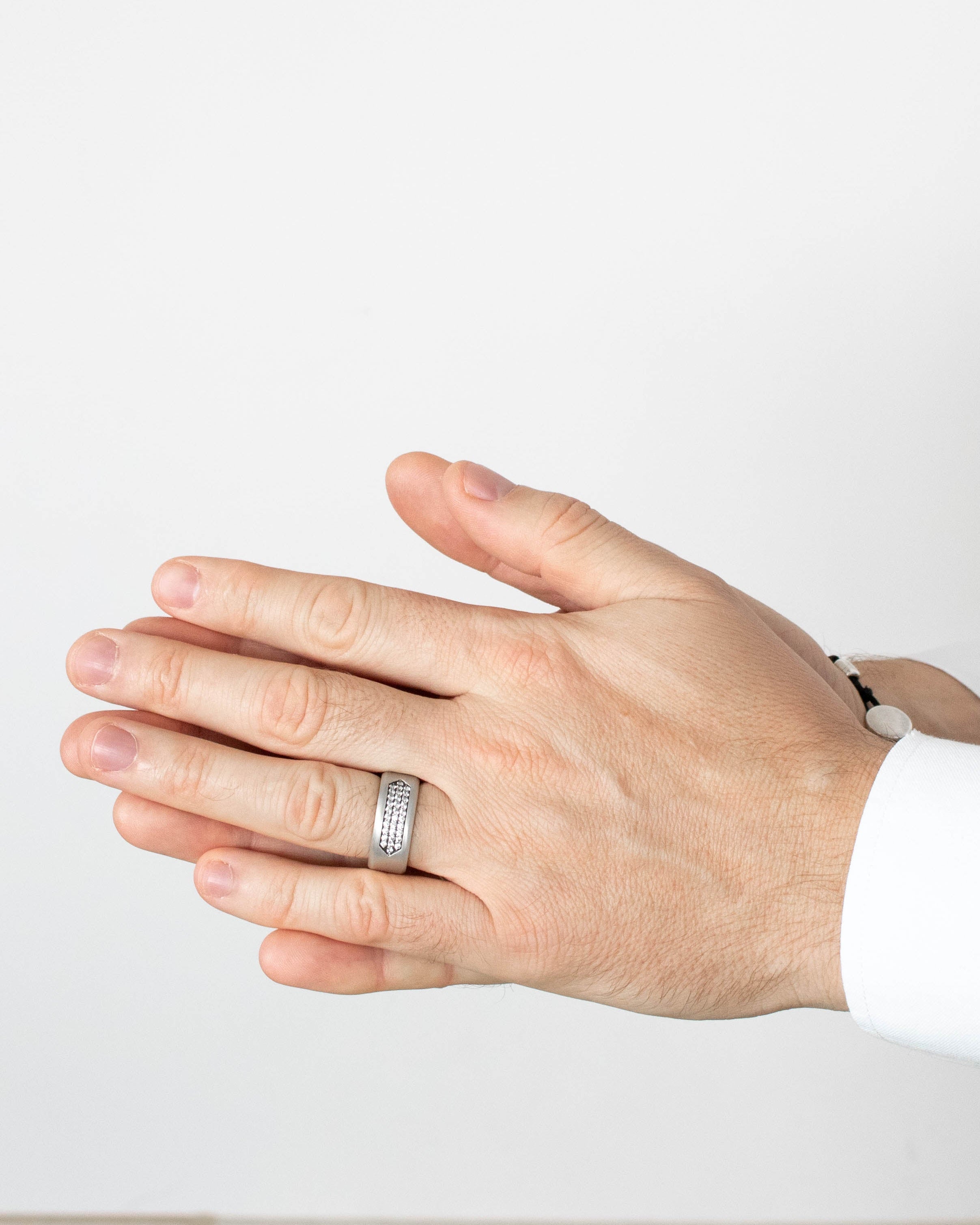 Hand wearing a silver ring on a plain background