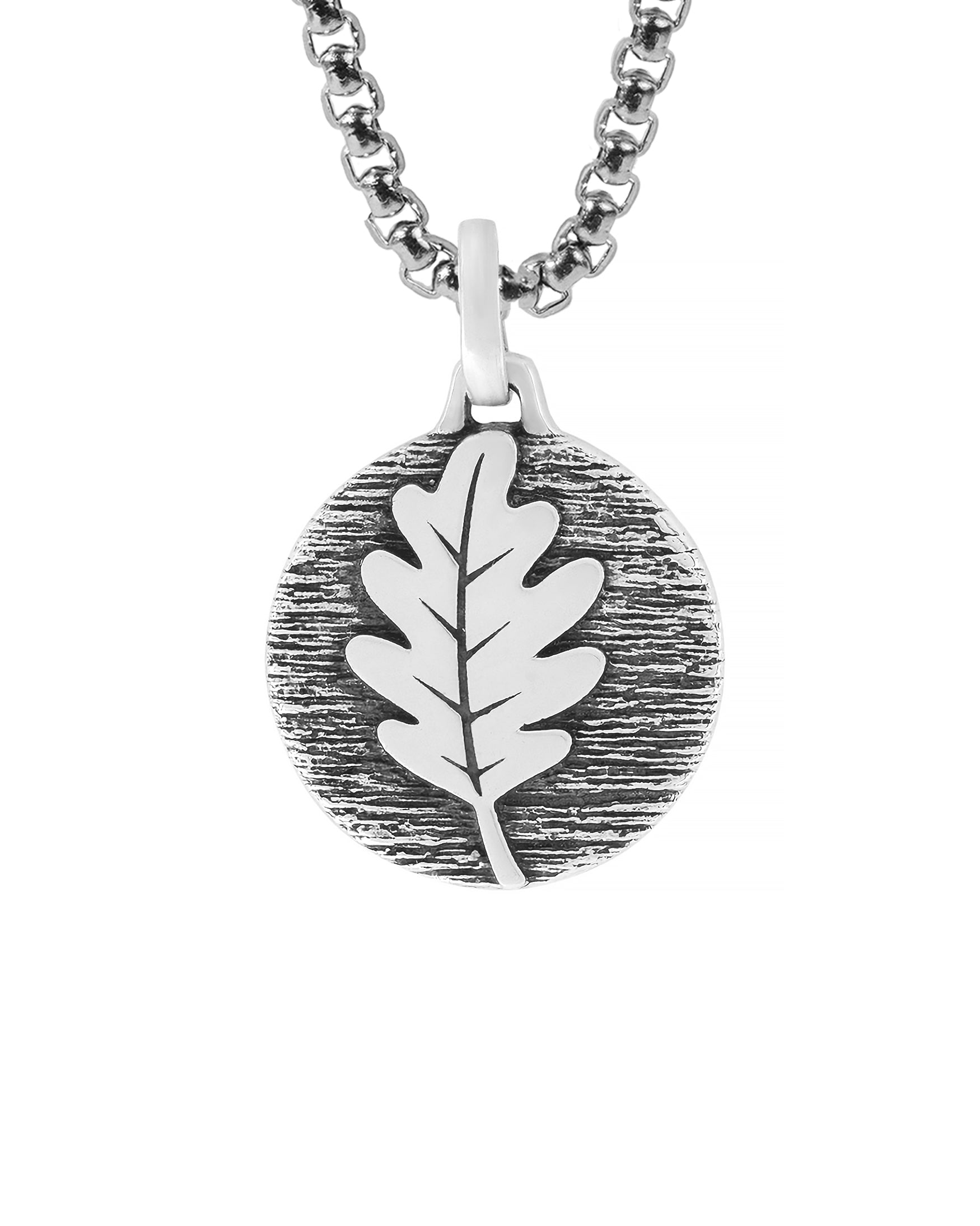 solid silver round pendant necklace with oak leaf on a tree bark.