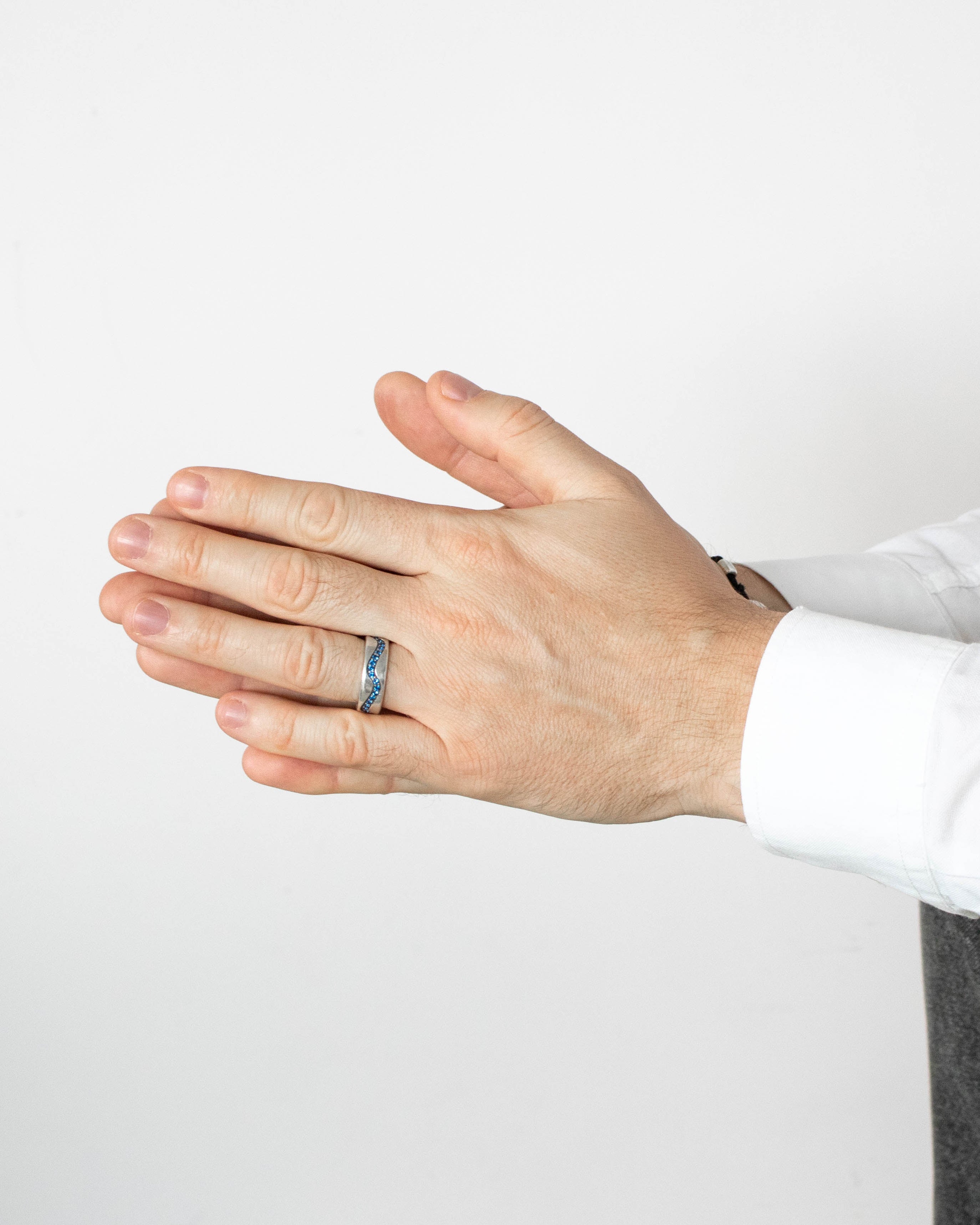 Hand wearing a ring on a plain background