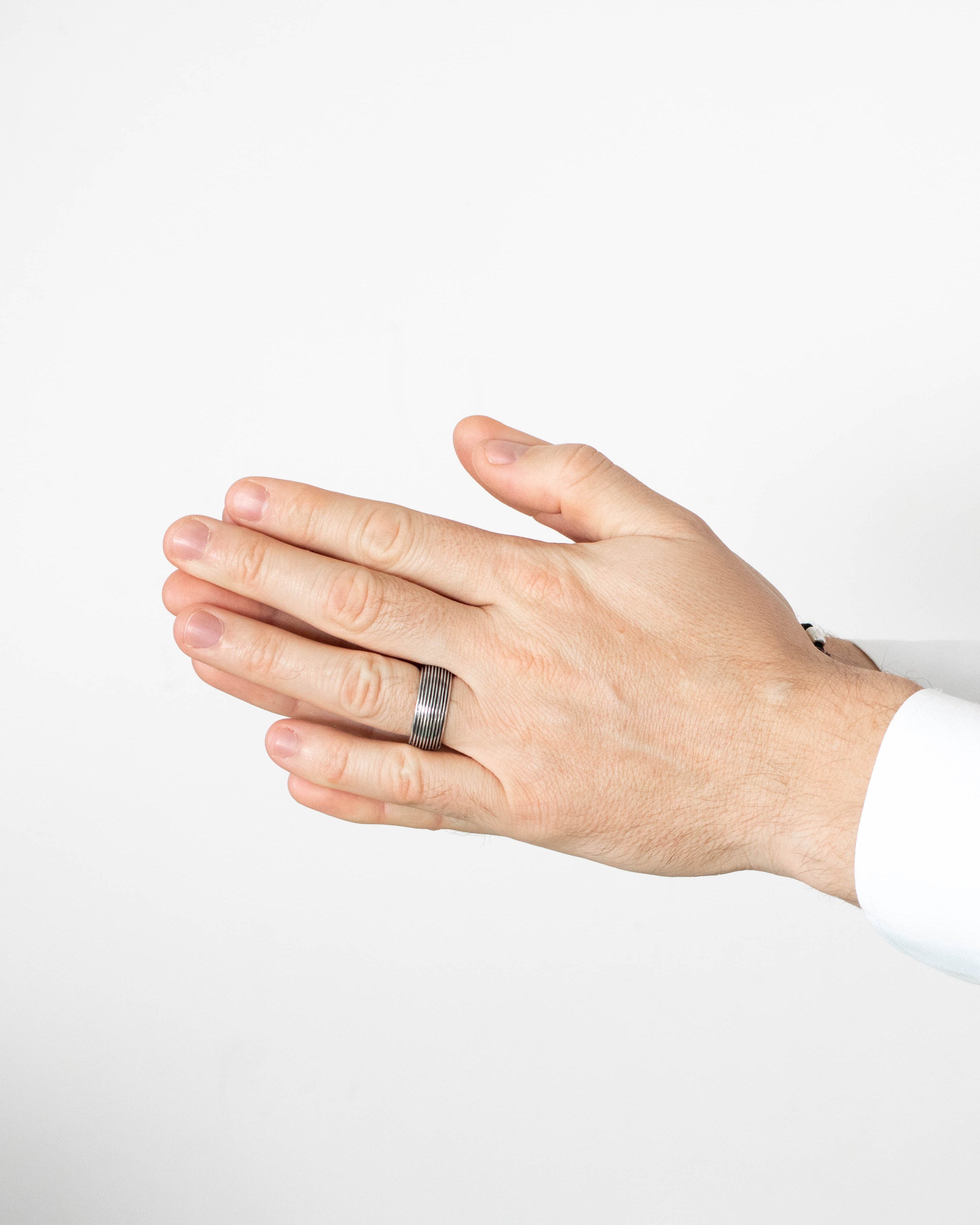 Hand wearing a silver ring on a white background