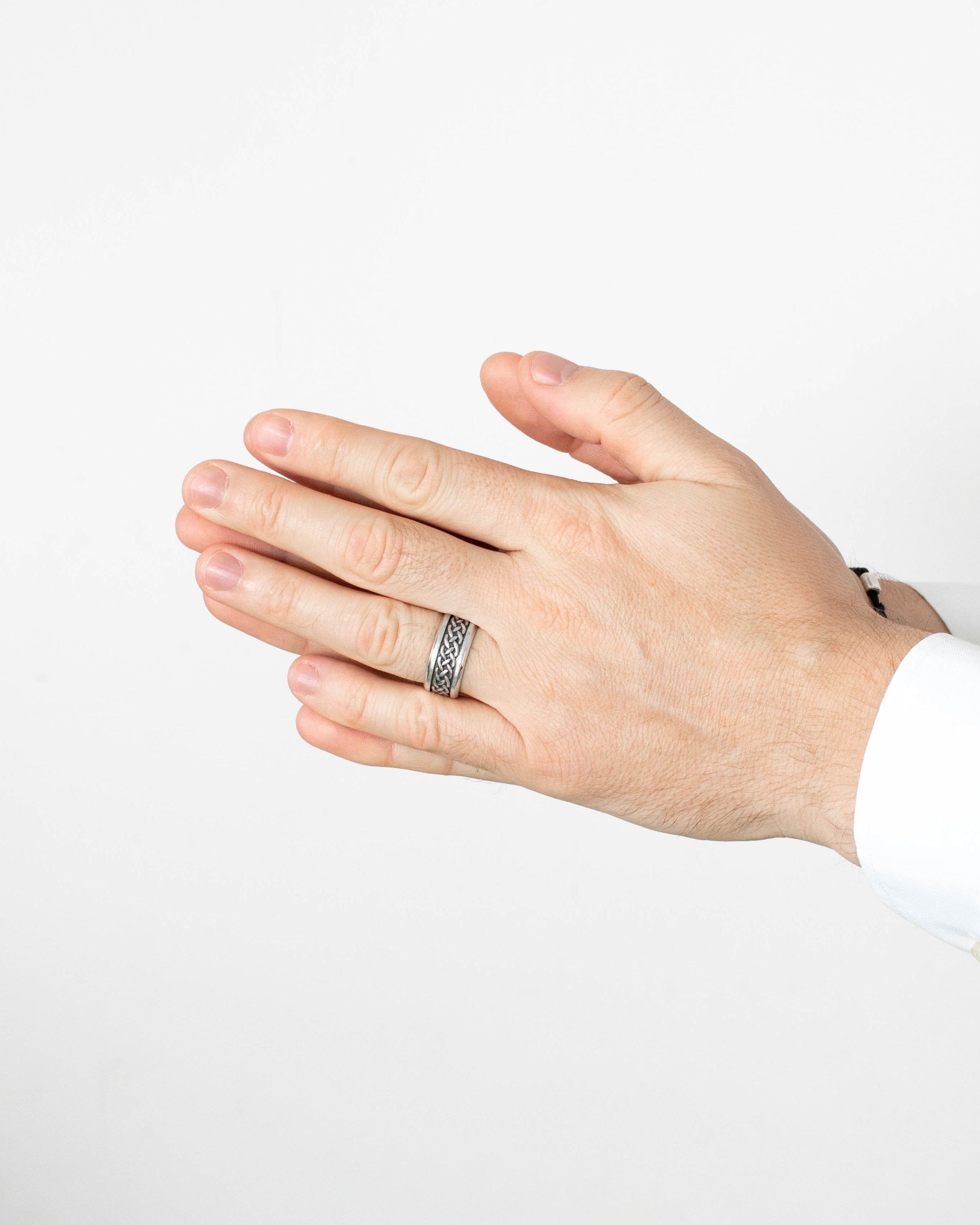 Hand wearing a silver ring on a plain background