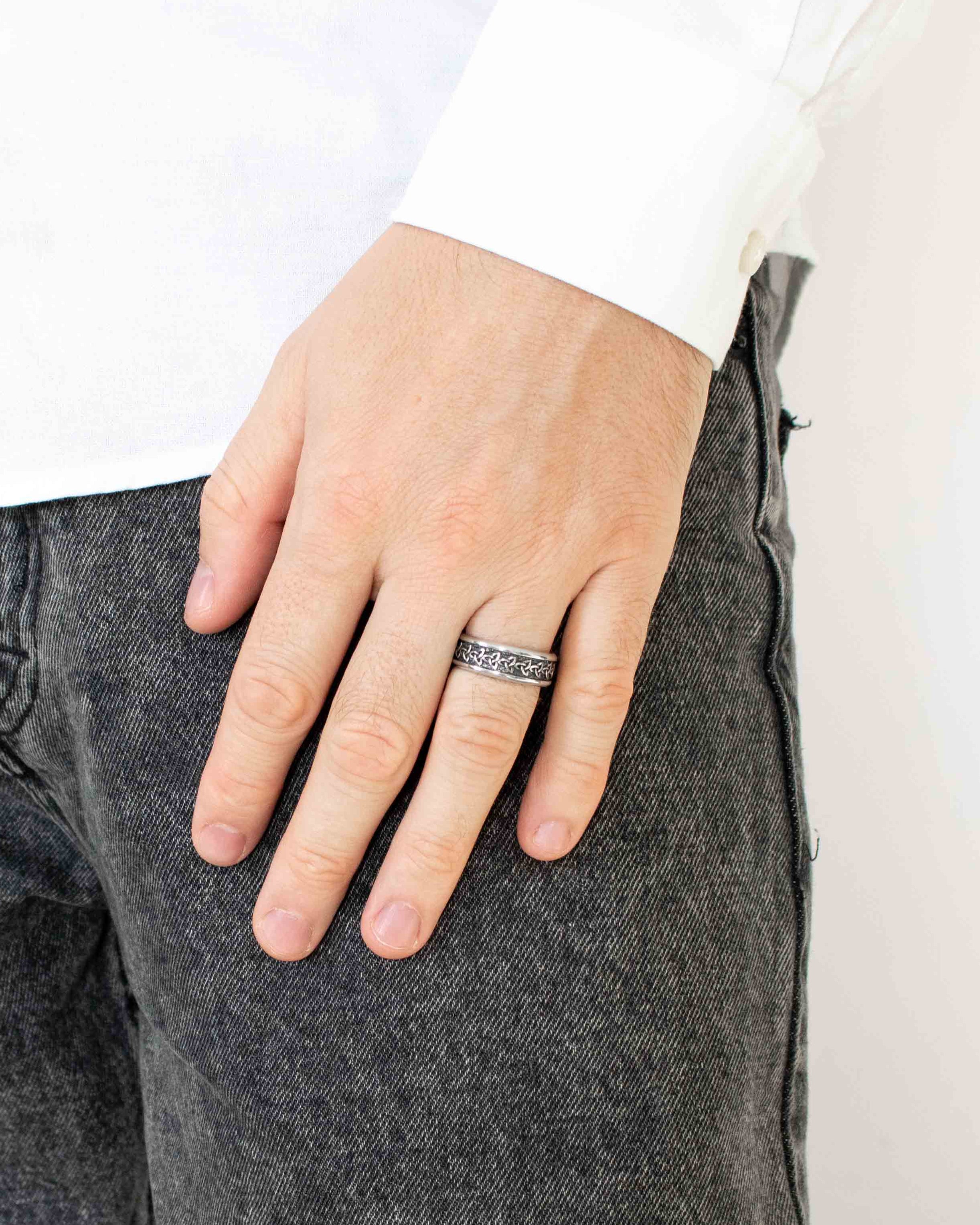 Person wearing a silver ring on a plain background