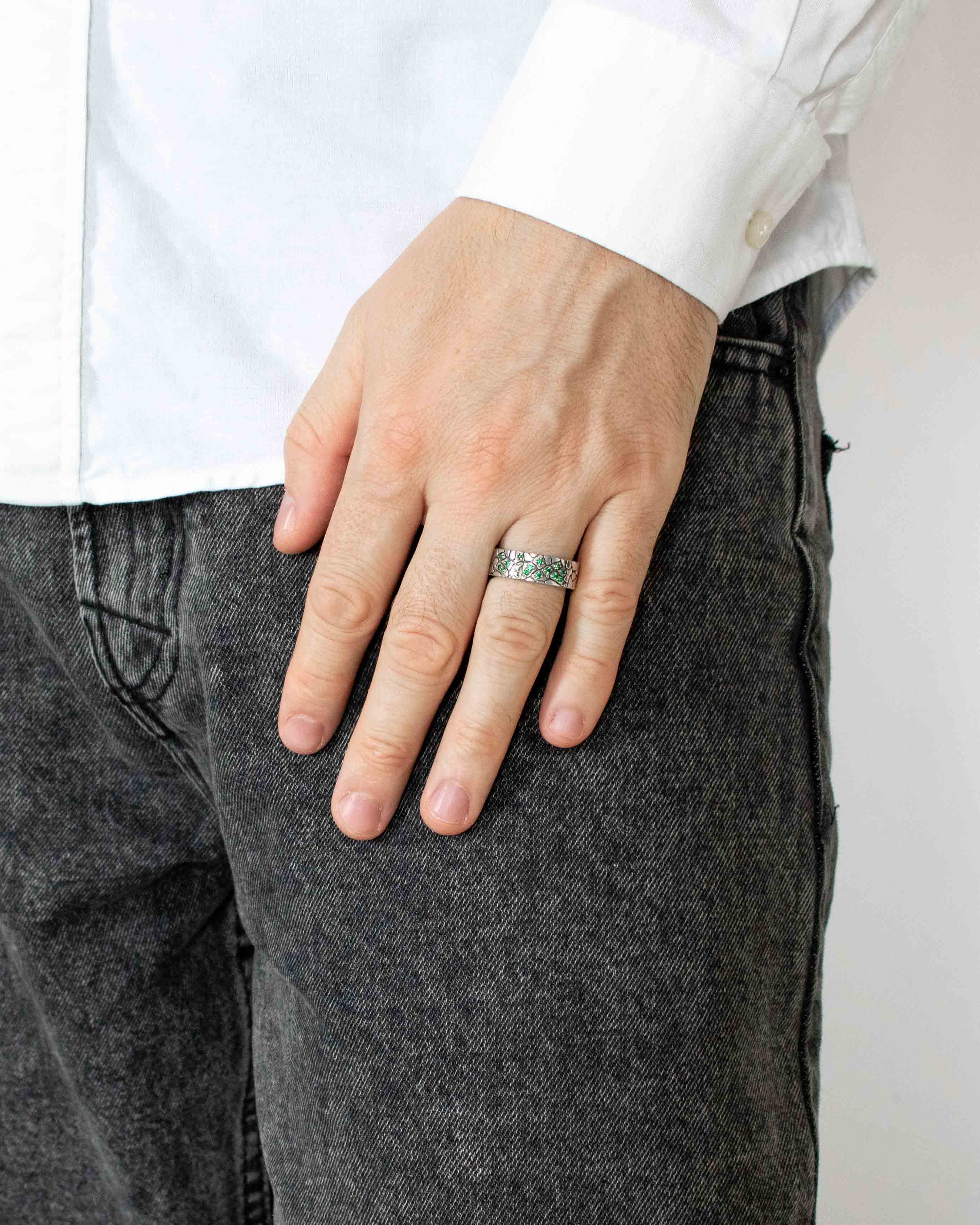 Person wearing a silver ring on a plain background