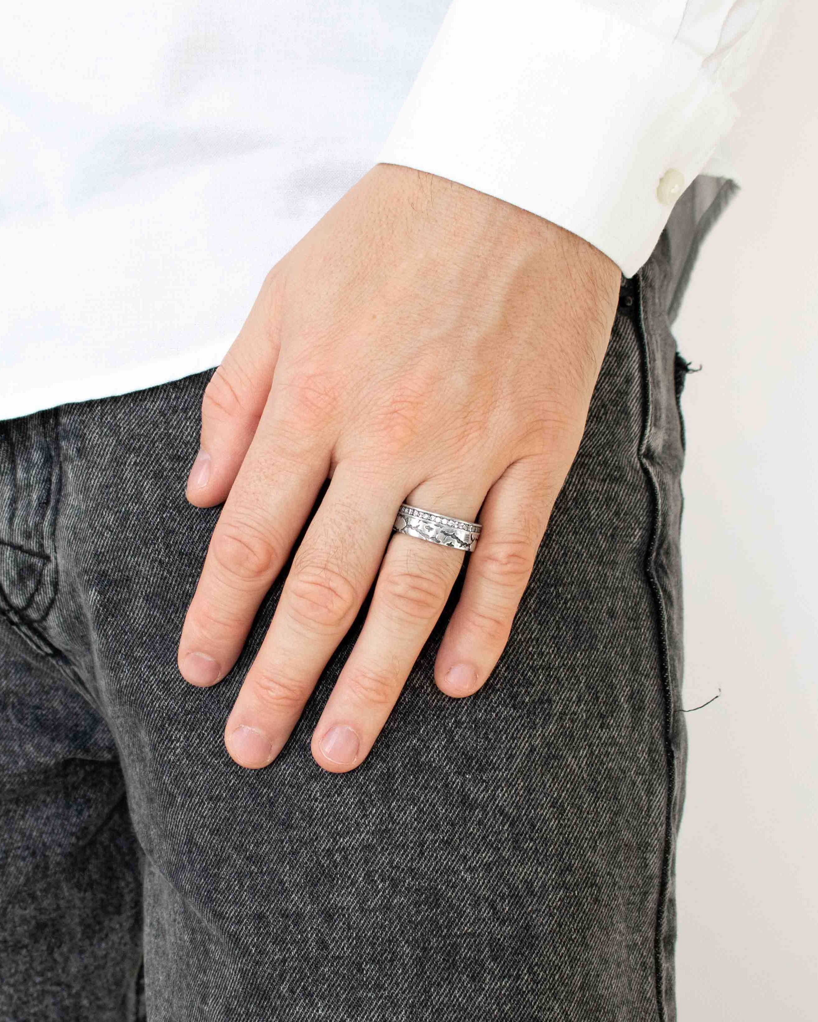 Hand wearing a silver ring with a white background