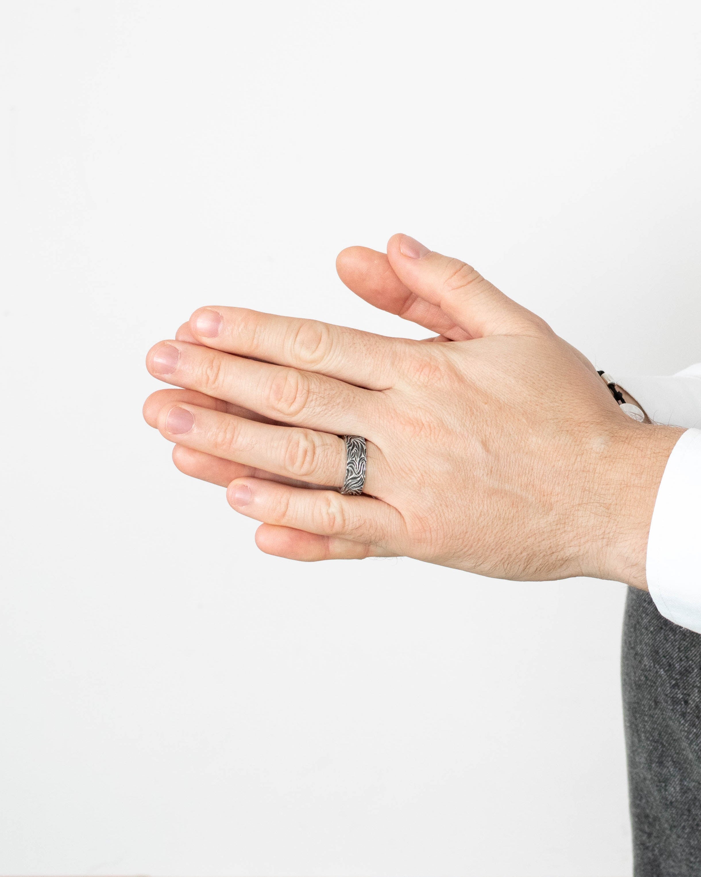 Hand wearing a silver ring on a plain background