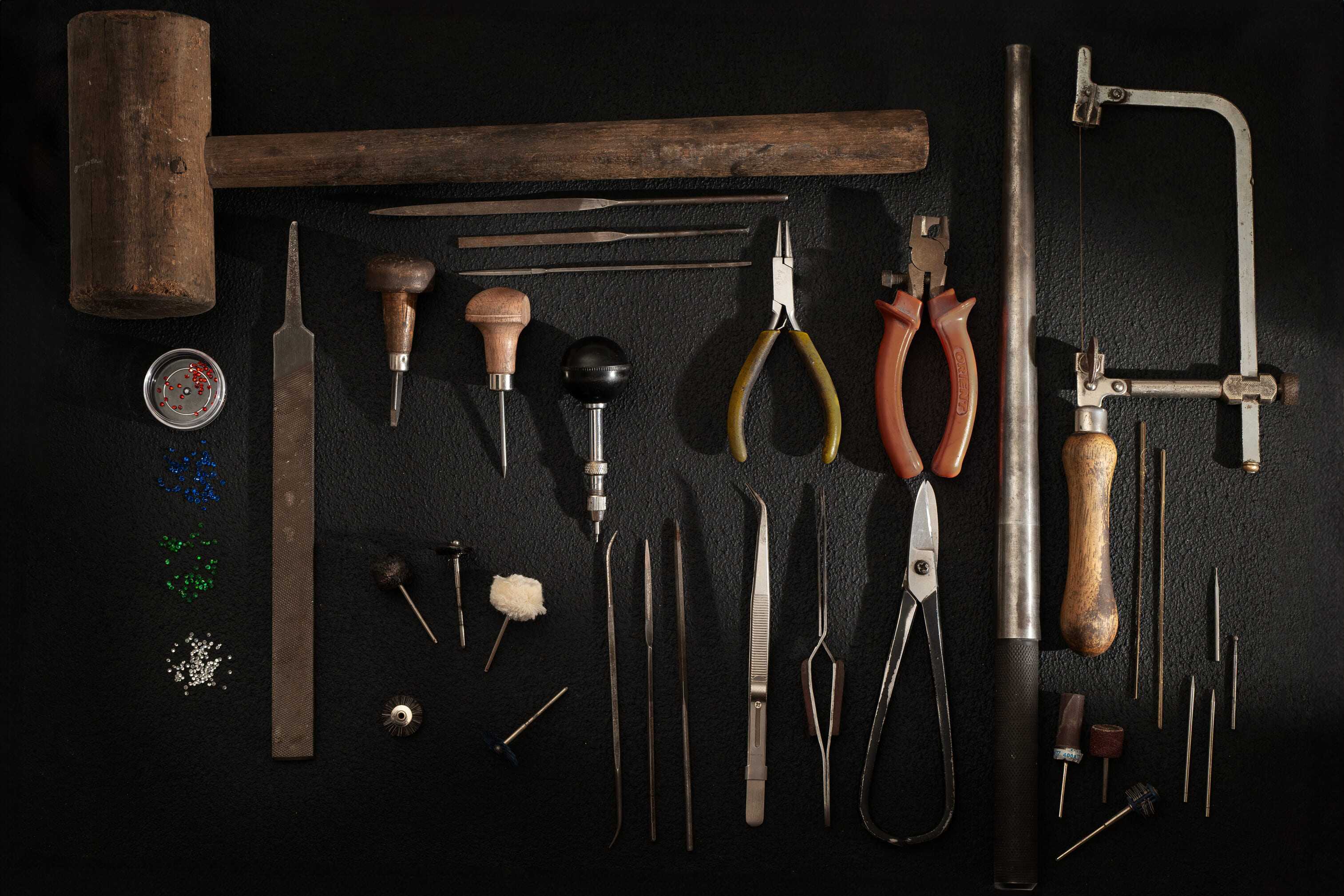 Collection of STRONZEN jewelry-making tools on a dark background.